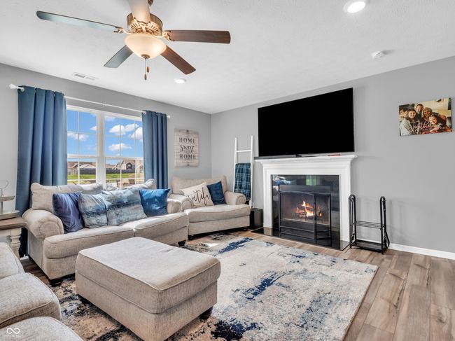 living room featuring a fireplace with flush hearth, visible vents, recessed lighting, beautiful flooring, and a ceiling fan | Image 14