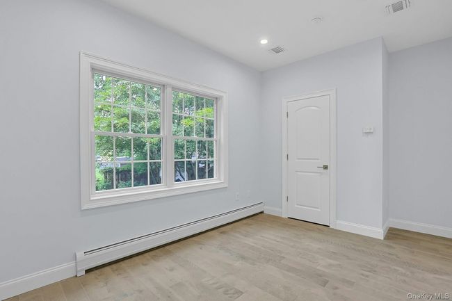 Empty room featuring a baseboard heating unit, light wood finished floors, and recessed lighting | Image 16