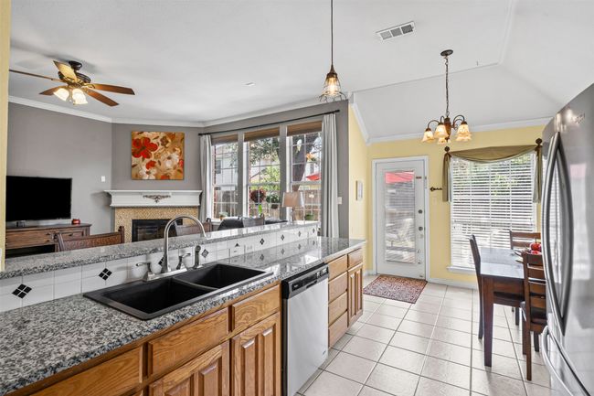 Kitchen featuring stainless steel appliances, a sink, a chandelier, brown cabinetry, and decorative light fixtures | Image 8