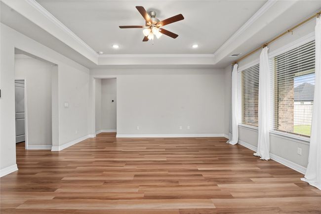 Spare room with crown molding, a ceiling fan, a raised ceiling, light wood-style flooring, and baseboards | Image 6