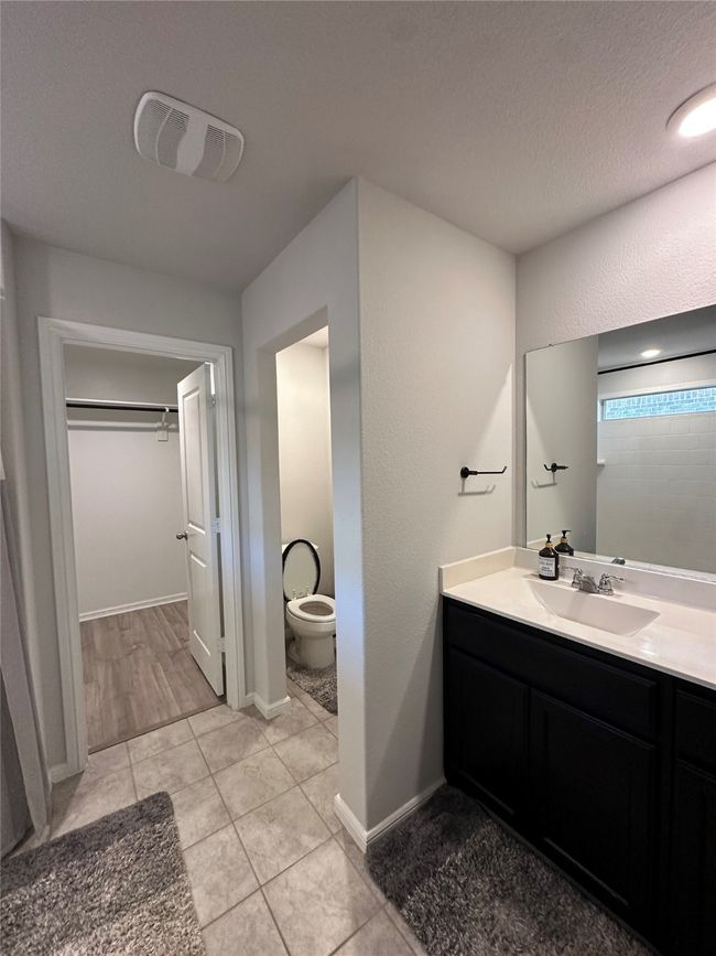 Bathroom featuring tile patterned floors, toilet, visible vents, vanity, and a walk in closet | Image 22