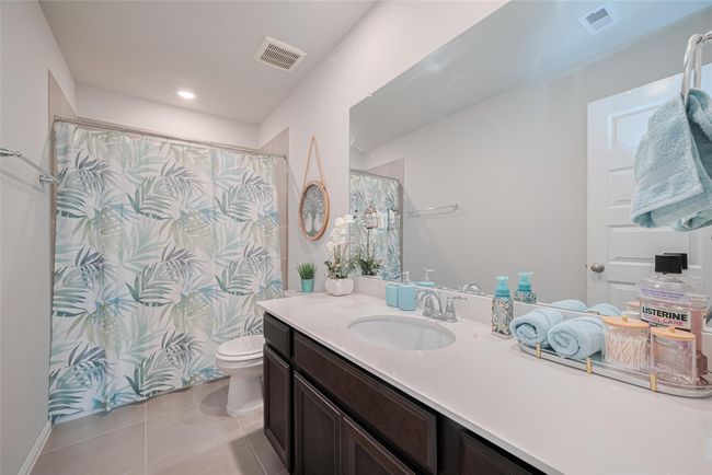 This is another full bathroom featuring a spacious vanity with a large mirror, light countertops, and dark cabinetry and a tub-shower combo. | Image 41