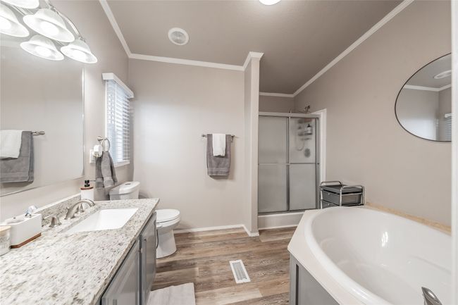 Bathroom with a shower stall, vanity, a garden tub, crown molding, and wood finished floors | Image 19