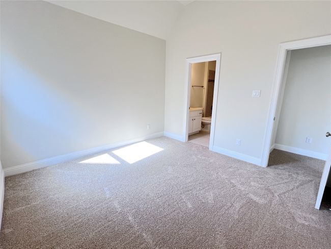 Unfurnished bedroom with light colored carpet, vaulted ceiling, and connected bathroom | Image 26
