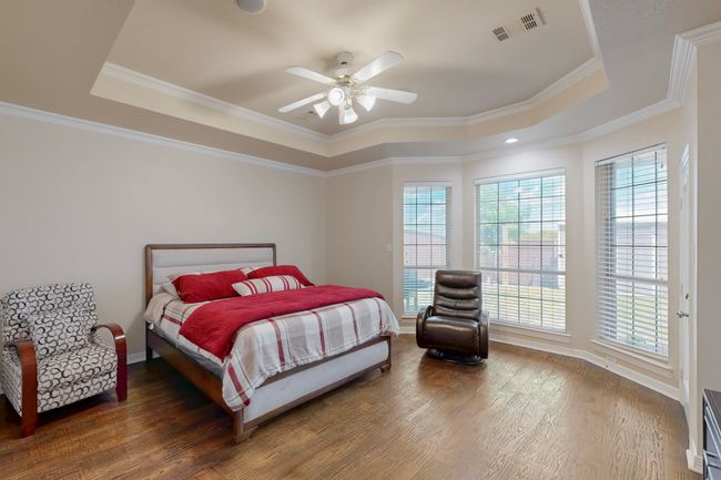 Bedroom featuring a raised ceiling, visible vents, and multiple windows | Image 17