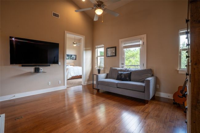Living area featuring ceiling fan, wood finished floors, and a high ceiling | Image 16