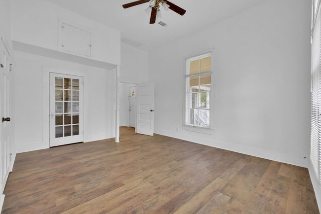 Unfurnished bedroom with ceiling fan, a high ceiling, wood finished floors, and visible vents | Image 18