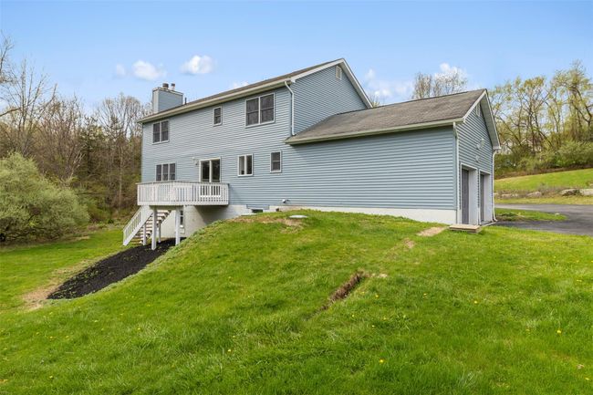 Back of property with a chimney, a yard, stairway, aphalt driveway, and a wooden deck | Image 33
