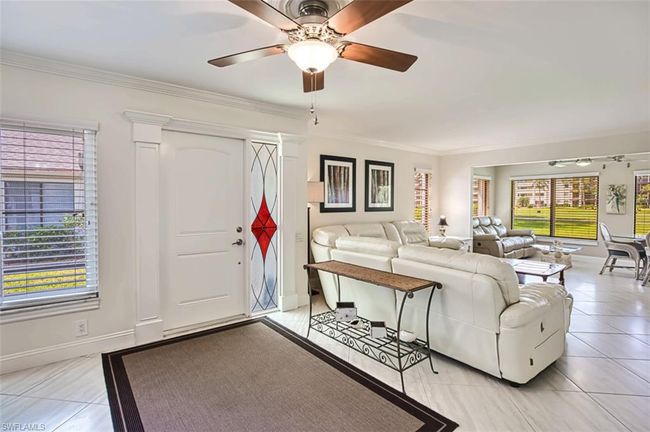 Living room featuring crown molding, a ceiling fan, light tile patterned floors, and baseboards | Image 10