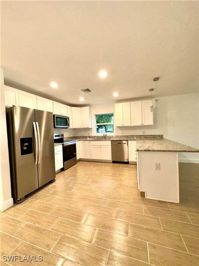 Kitchen featuring white cabinets, pendant lighting, appliances with stainless steel finishes, and kitchen peninsula | Image 4
