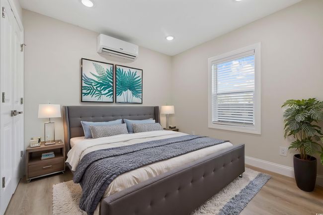 Bedroom featuring an AC wall unit, light wood-type flooring, baseboards, and recessed lighting | Image 33