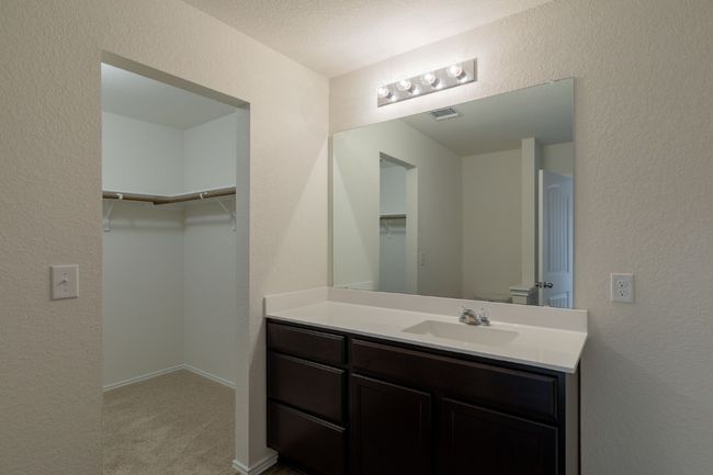 Bathroom featuring vanity, toilet, a walk in closet, and a textured wall | Image 10