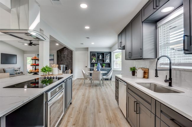 Kitchen with open floor plan, appliances with stainless steel finishes, island exhaust hood, light wood-style flooring, and light stone counters | Image 16