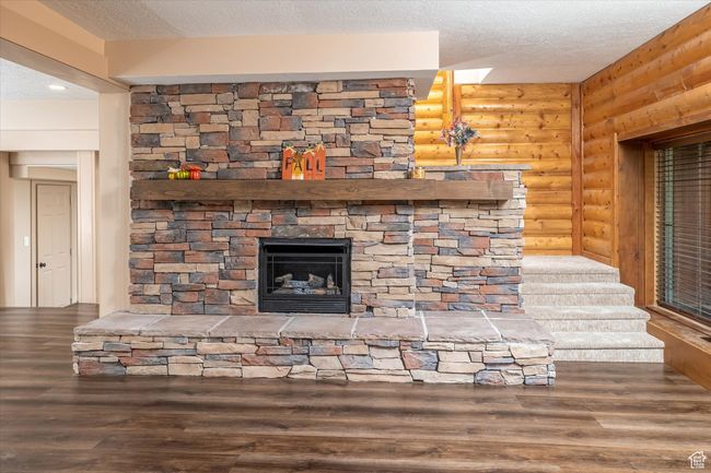 Detailed view of rustic walls, a textured ceiling, wood finished floors, and a fireplace | Image 23