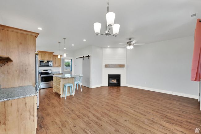 Kitchen featuring appliances with stainless steel finishes, a ceiling fan, a barn door, light wood-style flooring, and recessed lighting | Image 47
