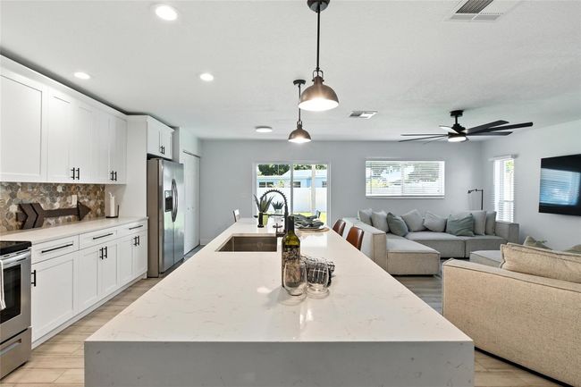 The oversized island is the true centerpiece—perfect for entertaining, casual meals, or homework while dinner’s being prepared! Wide open flow connects seamlessly to living and dining. | Image 9