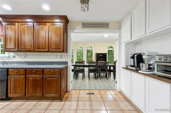 Kitchen with light tile patterned flooring, dark countertops, dishwasher, recessed lighting, and brown cabinets | Image 21
