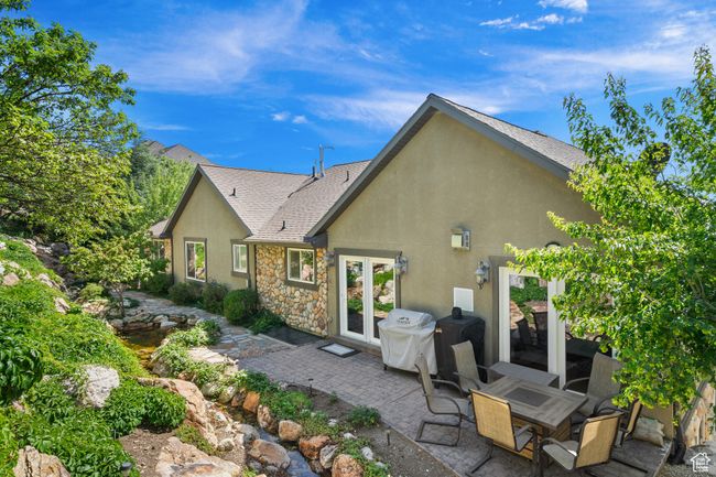 Back of house featuring a patio, stone siding, stucco siding, french doors, and a shingled roof | Image 38