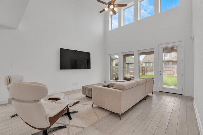 Living area with light wood-type flooring, a ceiling fan, and a towering ceiling | Image 18