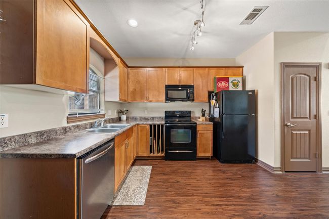Kitchen with black appliances, dark wood finished floors, and dark countertops | Image 4