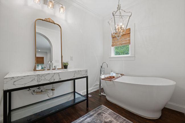Bathroom with wood finished floors, vanity, a chandelier, a freestanding bath, and ornamental molding | Image 23