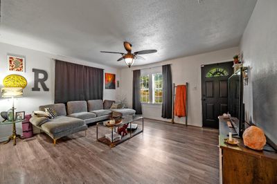 Living room featuring wood-type flooring, a textured ceiling, and ceiling fan | Image 3