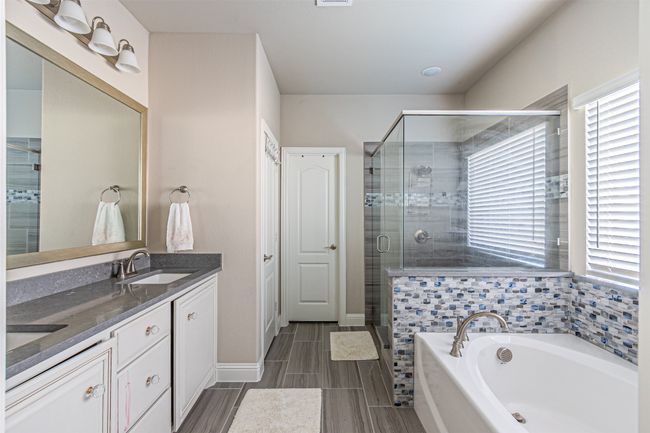 Full bathroom with a shower stall, double vanity, a garden tub, and baseboards | Image 19