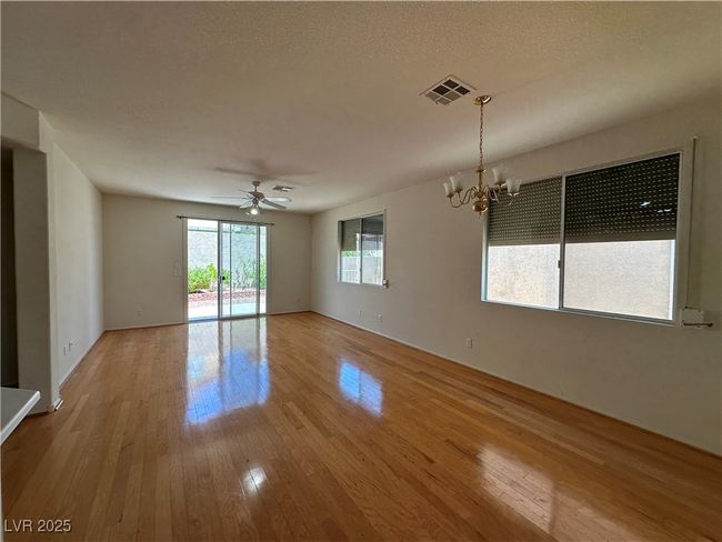 Empty room featuring wood finished floors, a chandelier, and ceiling fan | Image 9
