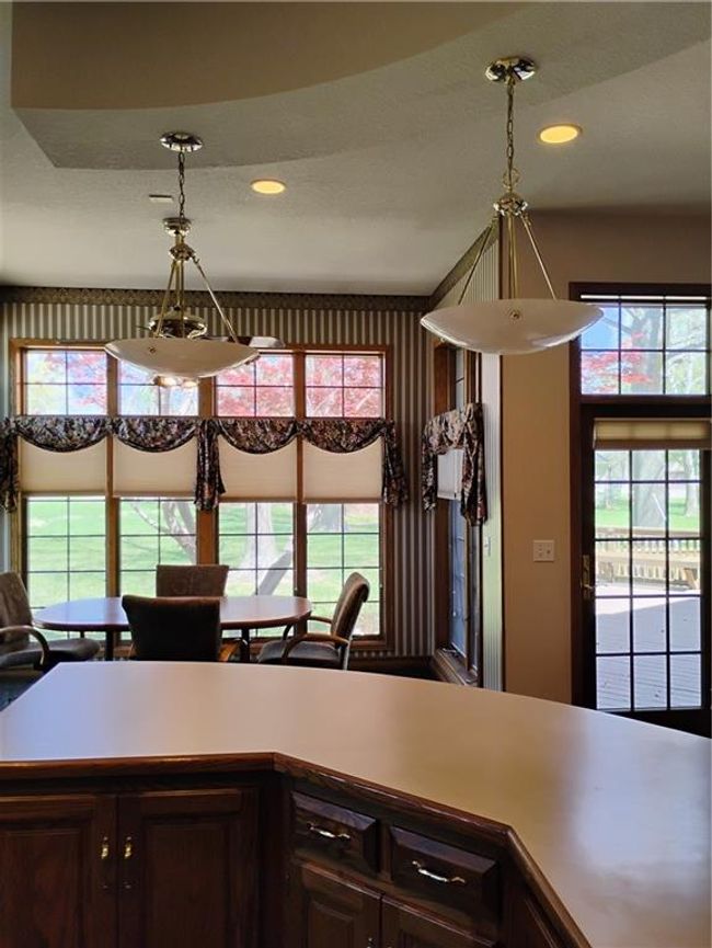 Kitchen featuring custom oak cabinets, light countertops, decorative light fixtures, and recessed lighting w/back door exit. | Image 36