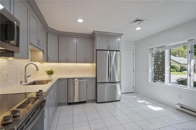 Eat-in kitchen with stainless steel appliances, tasteful backsplash, sink, gray cabinetry, and light tile patterned flooring | Image 2