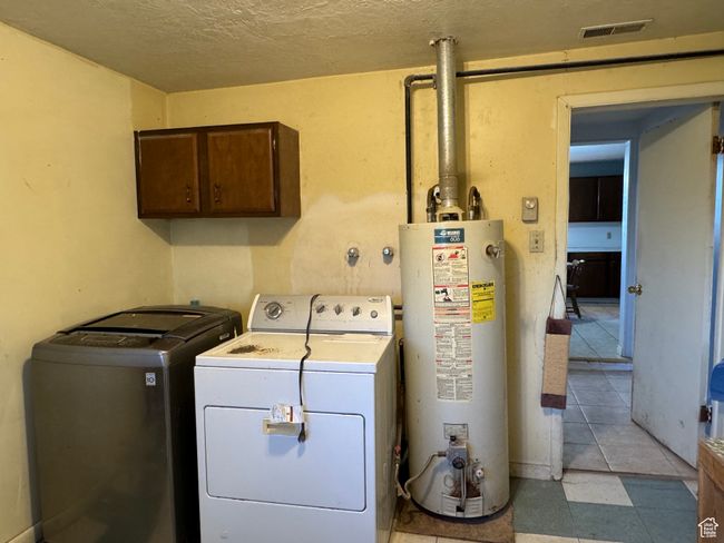 Laundry room with gas water heater, washing machine and dryer, cabinet space, and a textured ceiling | Image 22