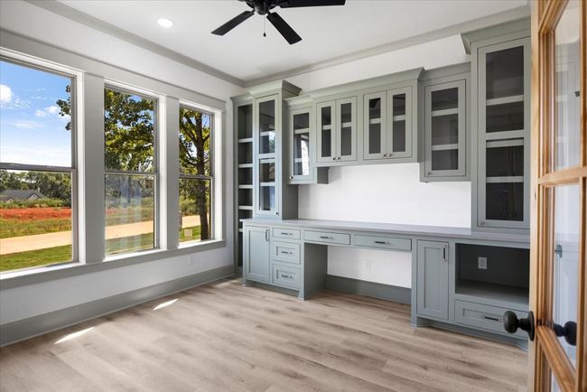 Unfurnished office featuring built in desk, light wood-type flooring, and a ceiling fan | Image 25
