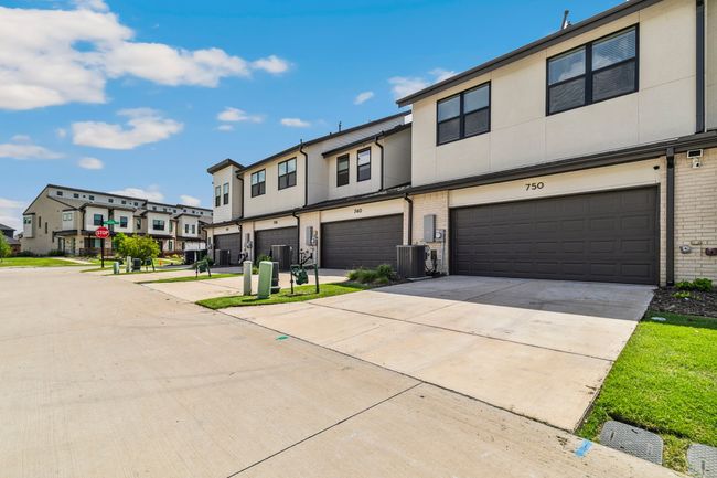 Townhome / multi-family property with a garage, a residential view, cooling unit, driveway, and stucco siding | Image 30