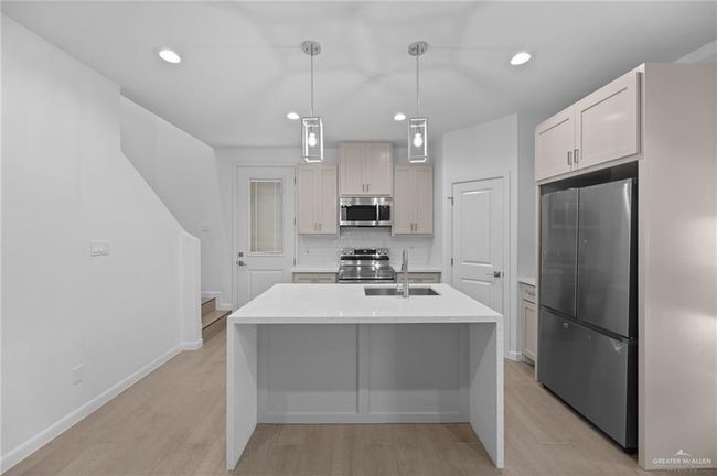 Kitchen featuring appliances with stainless steel finishes, light countertops, backsplash, a kitchen island with sink, and recessed lighting | Image 10
