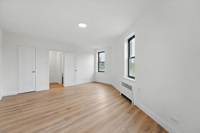 Unfurnished bedroom featuring baseboards, radiator heating unit, and light wood-type flooring | Image 15