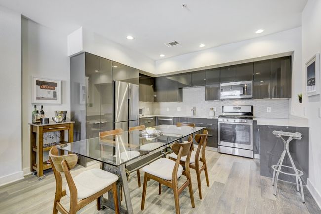 Kitchen with appliances with stainless steel finishes, modern cabinets, gray cabinets, light wood finished floors, and backsplash | Image 6