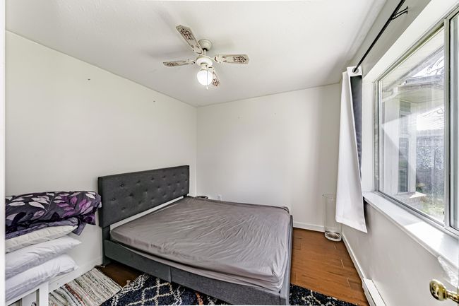 Bedroom with baseboard heating, a ceiling fan, baseboards, and wood finished floors | Image 12