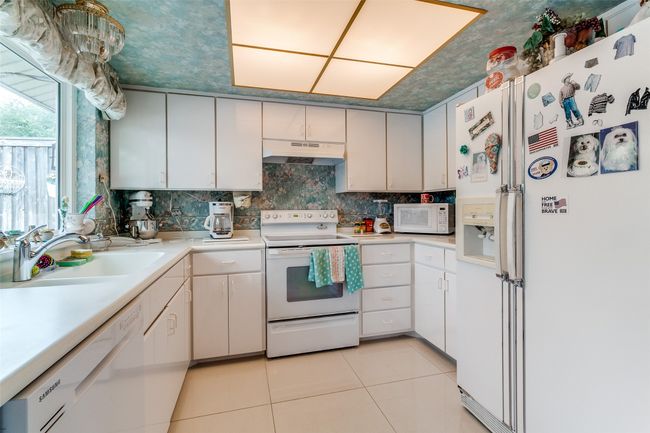 Kitchen featuring white appliances, under cabinet range hood, light tile patterned floors, light countertops, and tasteful backsplash | Image 11