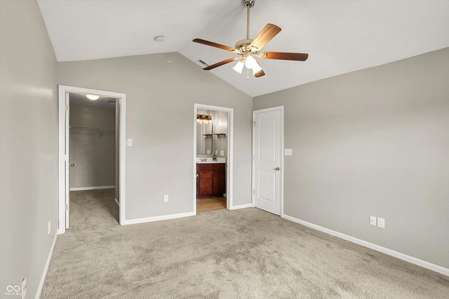 primary bedroom with a massive walk in closet, lofted ceiling, carpet flooring, and bathroom | Image 23