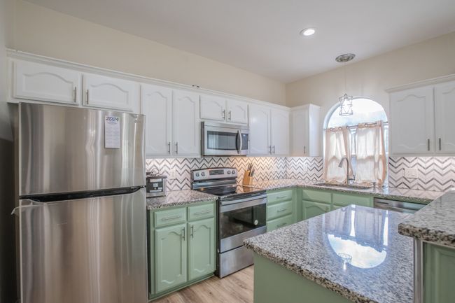 Kitchen featuring white cabinetry, green cabinets, stainless steel appliances, and a sink | Image 9