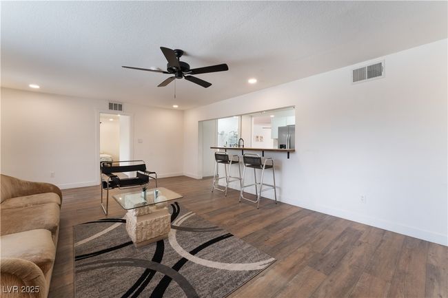 Living room with a ceiling fan, wood finished floors, recessed lighting, and visible vents | Image 15