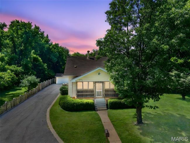 View of front facade featuring a yard, covered porch, and a garage | Image 32