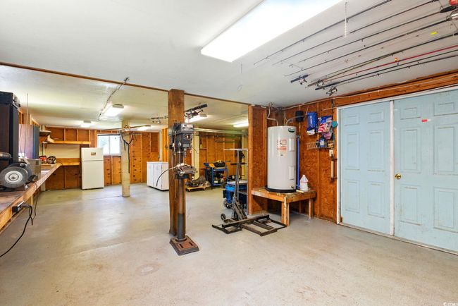 Basement featuring electric water heater, freestanding refrigerator, washer / clothes dryer, and a workshop area | Image 33