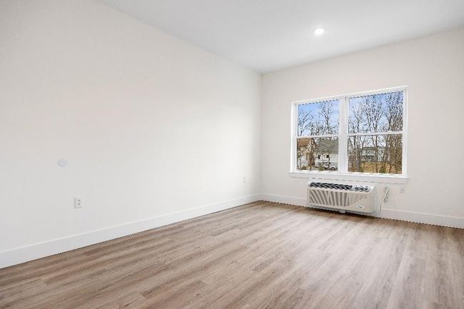 Unfurnished room featuring light wood-style flooring, baseboards, a wall mounted air conditioner, and recessed lighting | Image 18