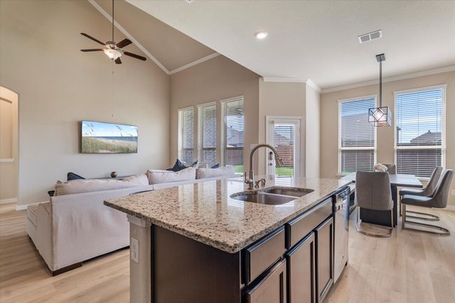 Kitchen with a sink, light wood-style floors, crown molding, open floor plan, and lofted ceiling | Image 13