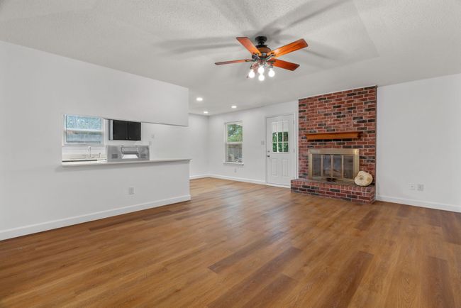 Unfurnished living room with a ceiling fan, wood finished floors, a fireplace, a textured ceiling, and recessed lighting | Image 9