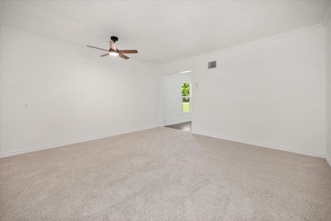Empty room with ceiling fan, crown molding, and carpet | Image 20