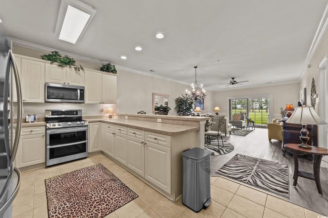 Kitchen featuring appliances with stainless steel finishes, a peninsula, light countertops, light tile patterned floors, and recessed lighting | Image 4