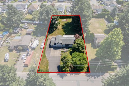 Expansive property featuring a large residence, attached garage, paved driveway, mature trees, and a spacious green lawn | Card Image