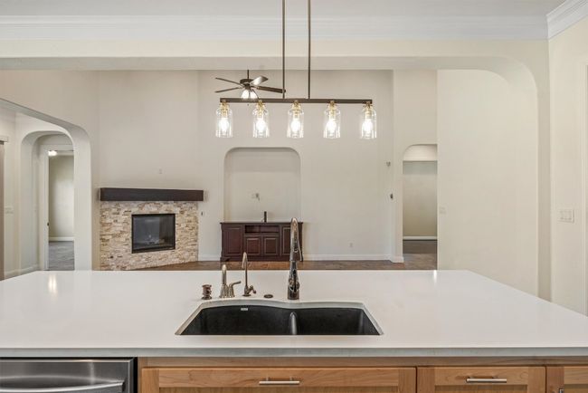 Kitchen opens to the living area, featuring arched walkways, open floor plan, ceiling fan, pendant lighting, and ornamental molding | Image 18